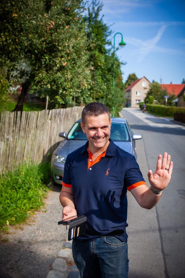 Martin mit Handy in Hand blickt freundlich mit Blick zum Kunden und ist bereit Termin aufzunehmen